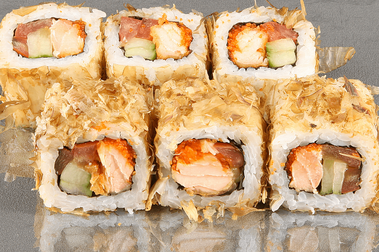 Ролл с обжареным филе лосося с соусом терияки, помидором, хрустящим огурцом, икрой капеллана масаго в тончайшей стружке копчёного тунца. Кадзуми