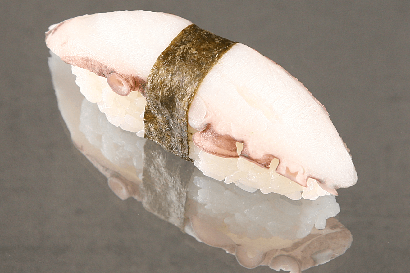 Суши нигири с мясом осьминога, обёрнутый полоской нори. Тако