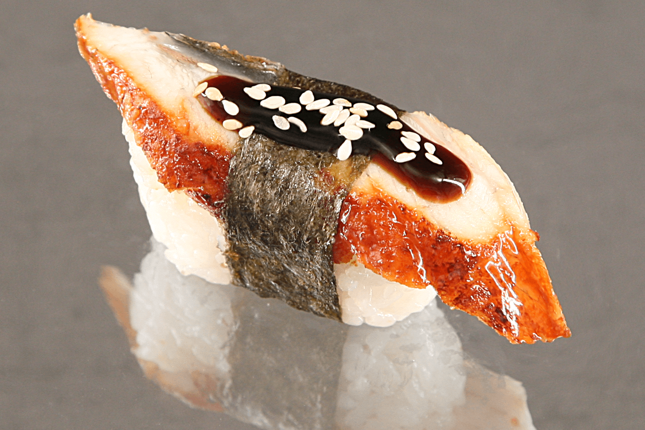 Суши нигири с подкопчёным угрём, приправленным соусом унаги и зёрнышками светлого слегка обжаренного кунжута. Унаги