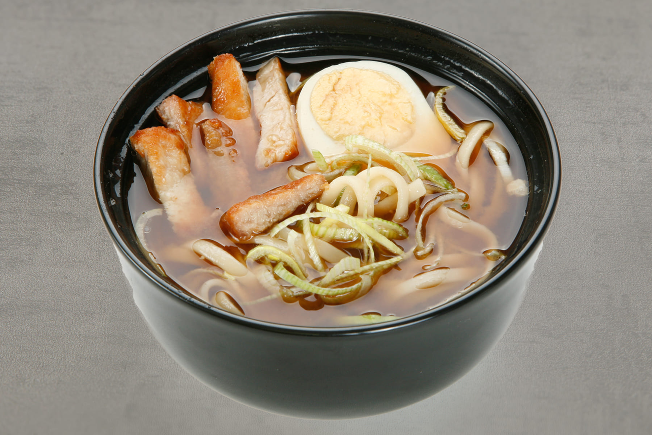 Ароматный суп с лапшой удон, с ломтиками свинины, яйцом, украшен луком порей. Нику Рамен